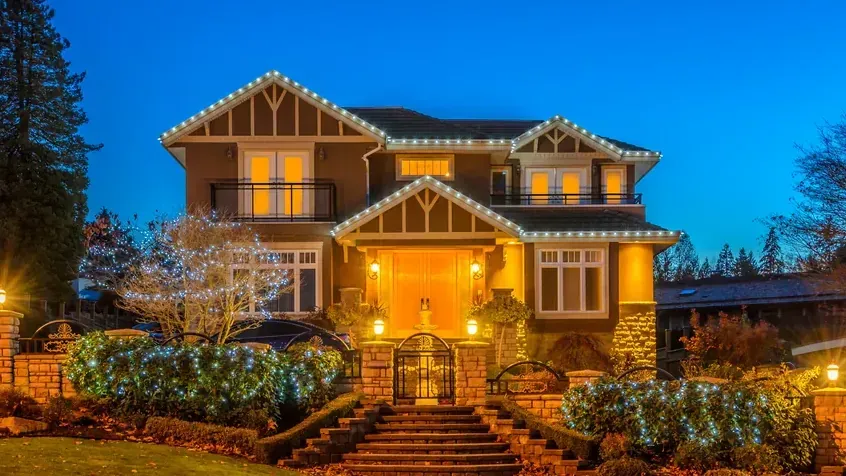 Front steps and entry lined with warm Christmas lights at night