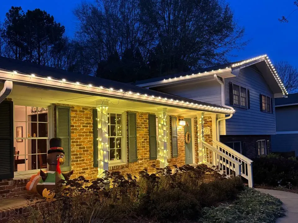 Brick ranch with a lit roofline and wrapped porch columns at dusk